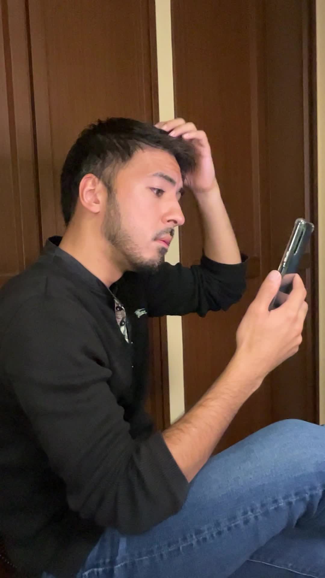 スマホを片手で持ち、もう片手で頭を触りながら考え込む