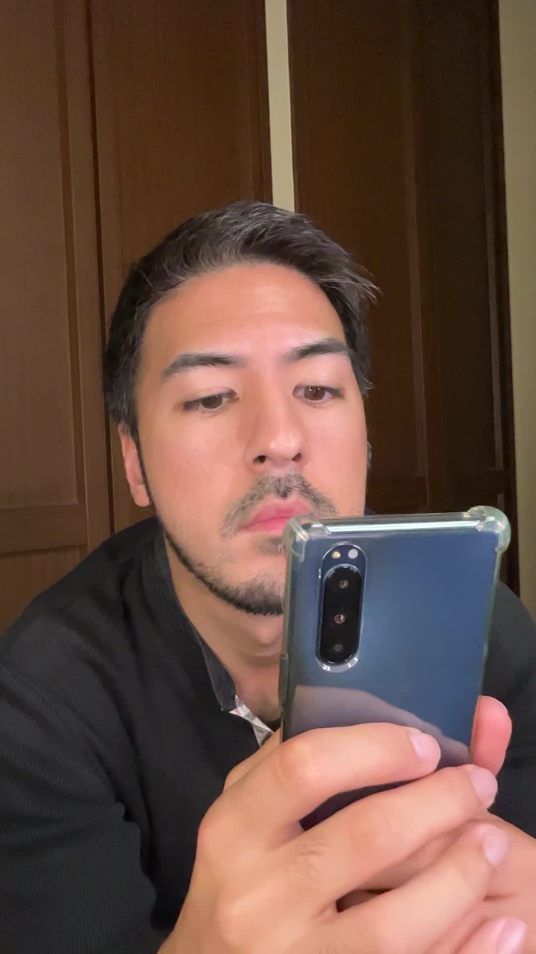 スマホを両手で持ち、AGAクリニックの評判をじっくり確認している様子