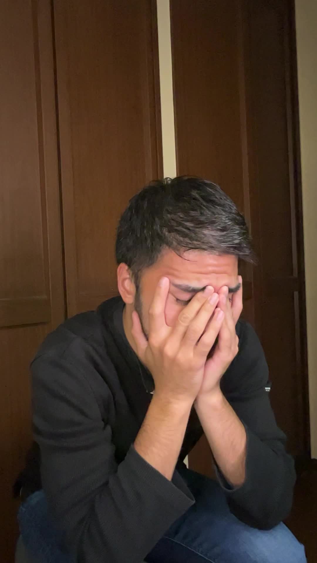 椅子に腰掛け、両手で顔を覆い、悩んでいる様子を表現する