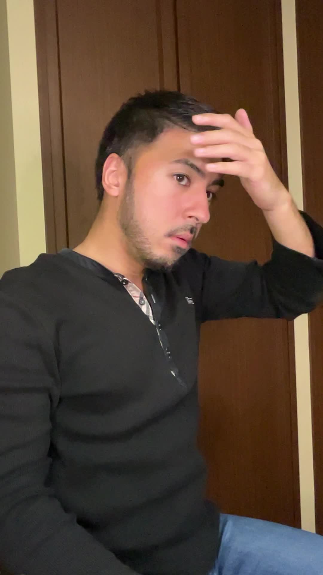 椅子に座りながら、手で髪を軽く整える自然な仕草をする