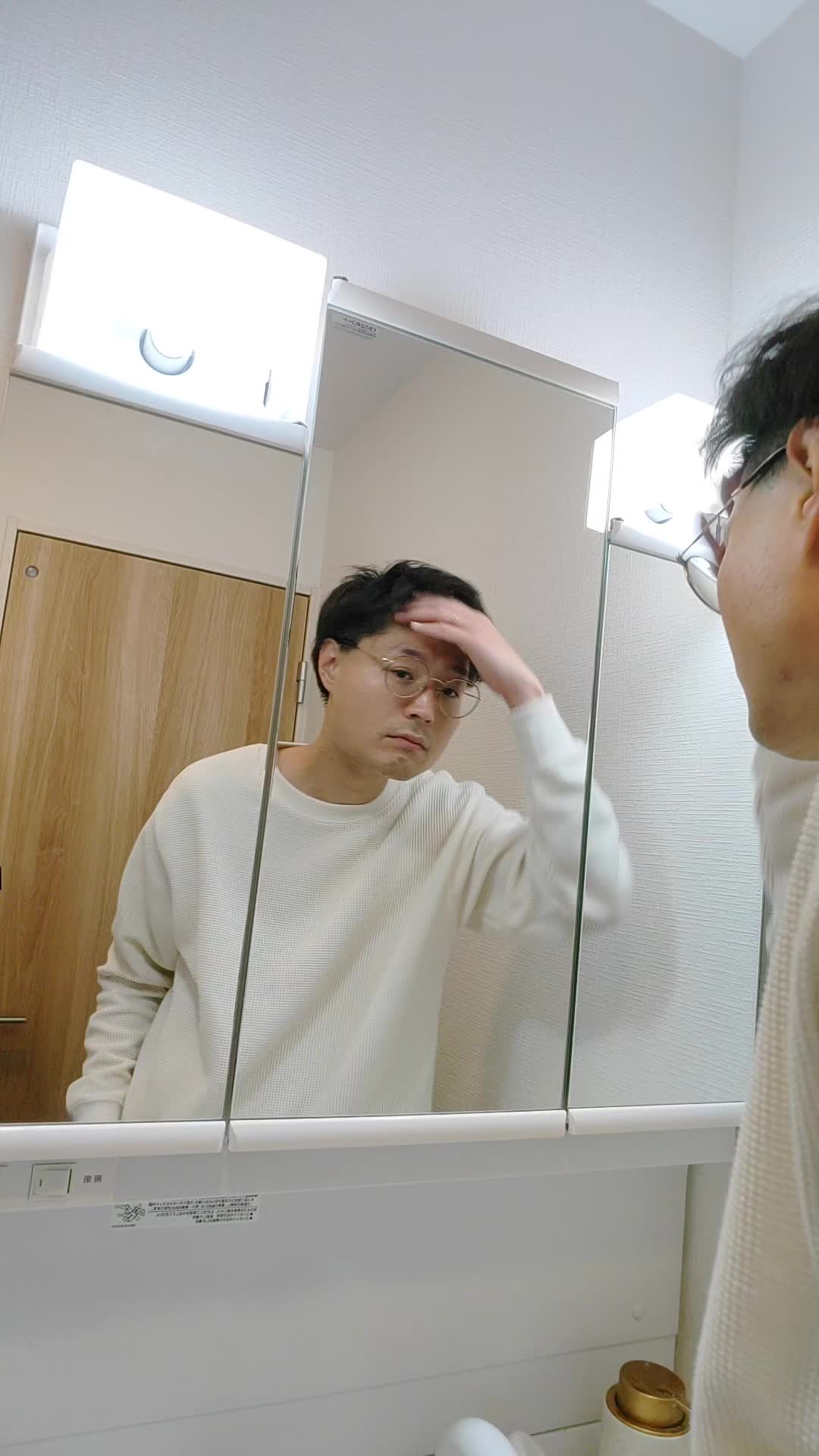 鏡の前で髪を軽くかき上げながら、自分の姿を確認する