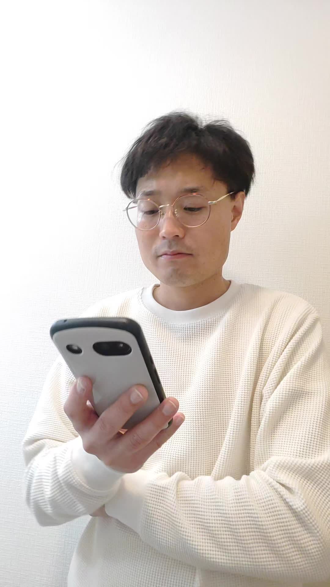 スマホを持ったまま、少し俯き加減で考え込む仕草をする