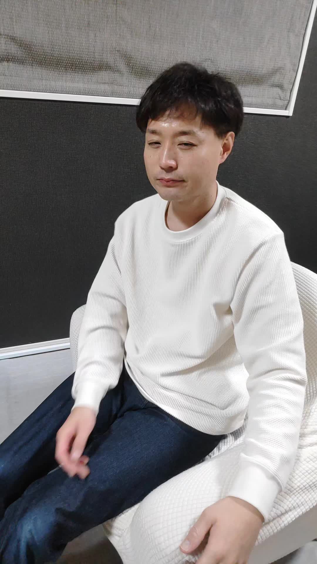 椅子に座りながら、手で髪を軽く整える自然な仕草をする