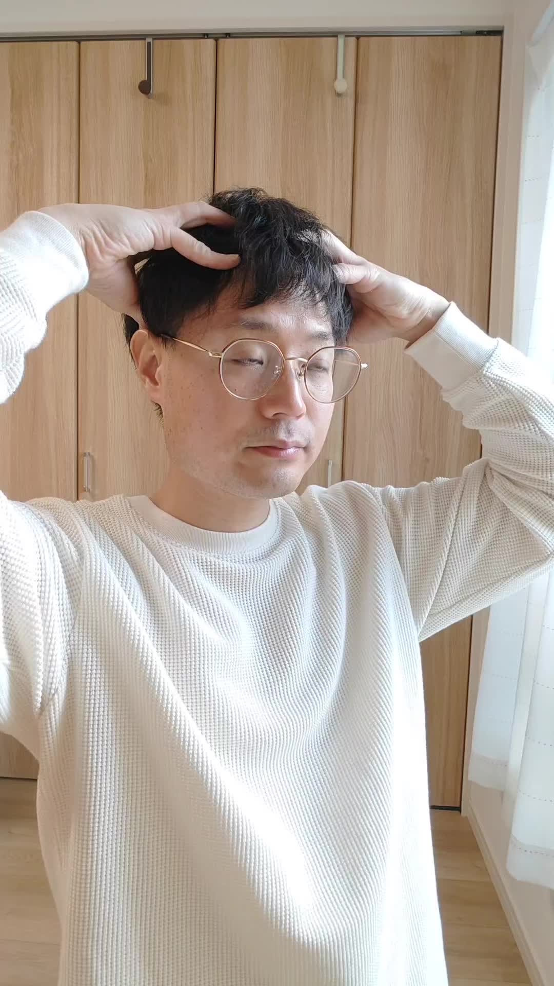 頭皮を指で押さえながら、真剣に自分を見つめている表情をする