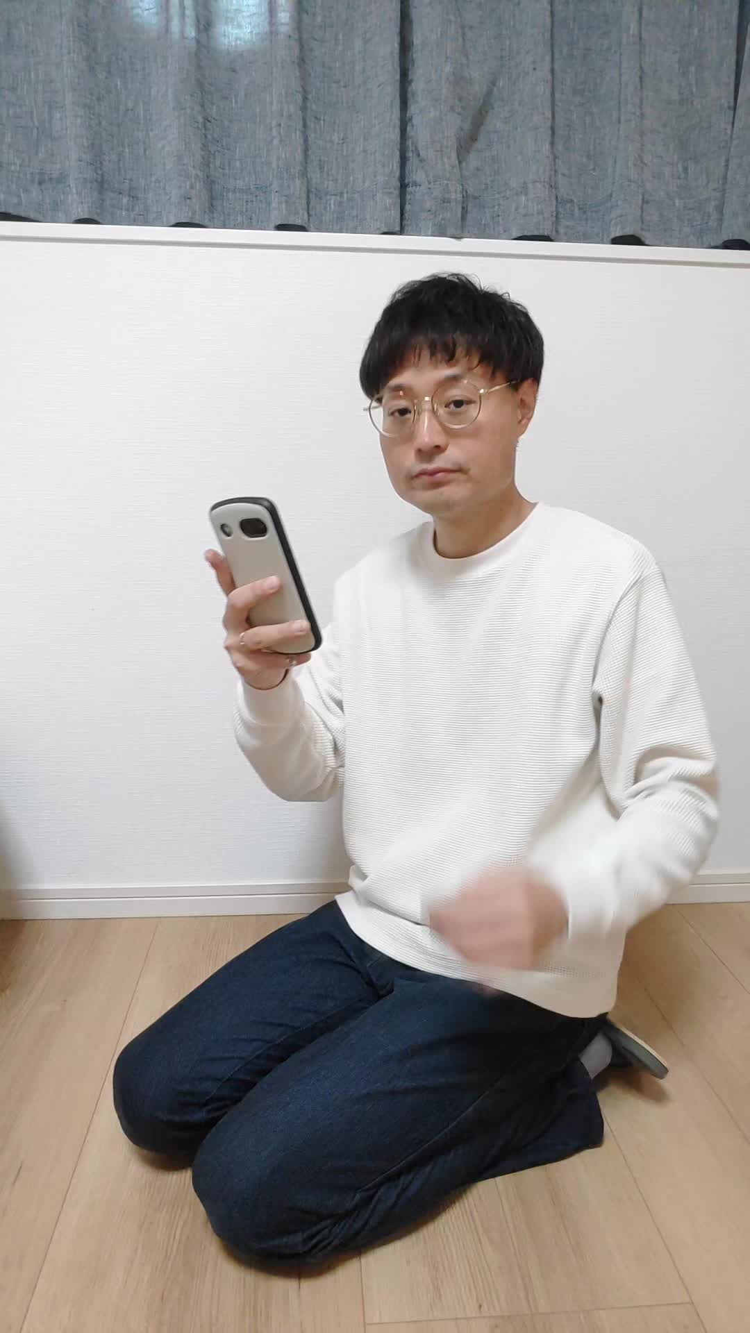 床に膝をつき、スマホを持って頭頂部を確認する仕草をする