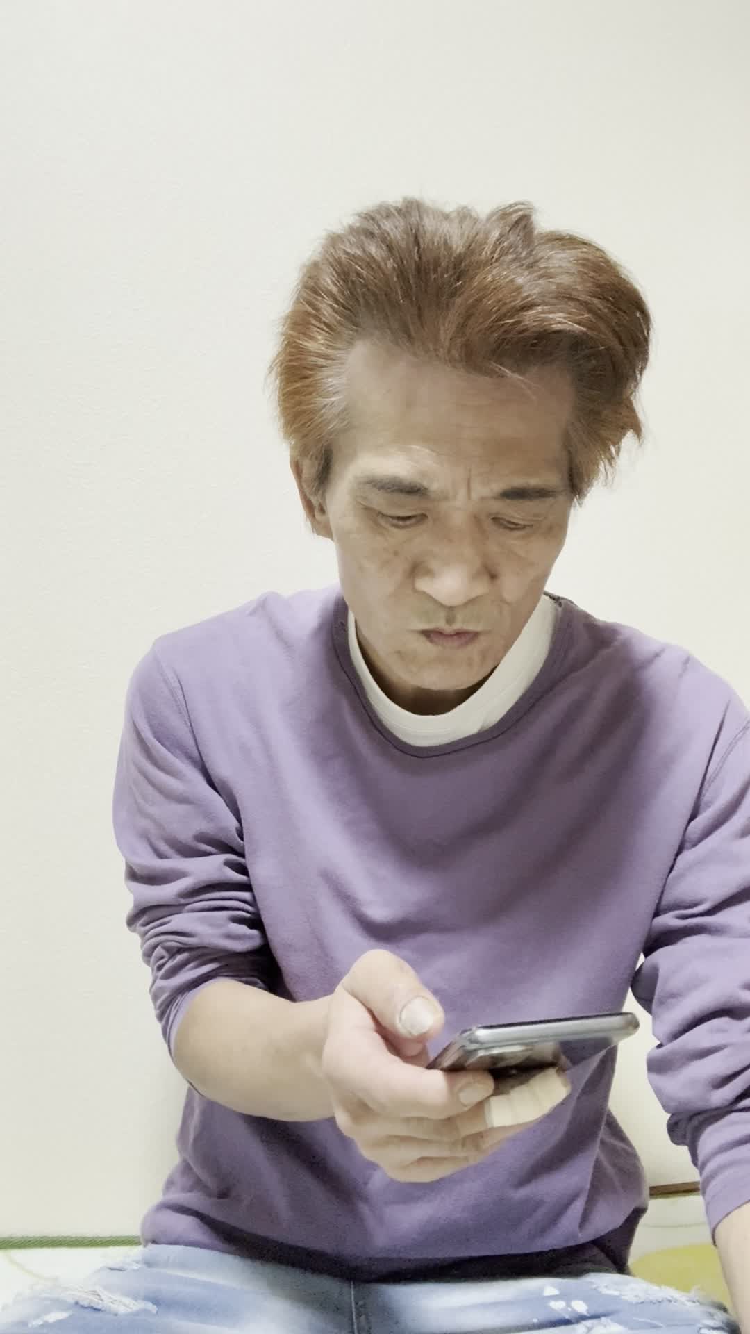 スマホを持ったまま、少し俯き加減で考え込む仕草をする