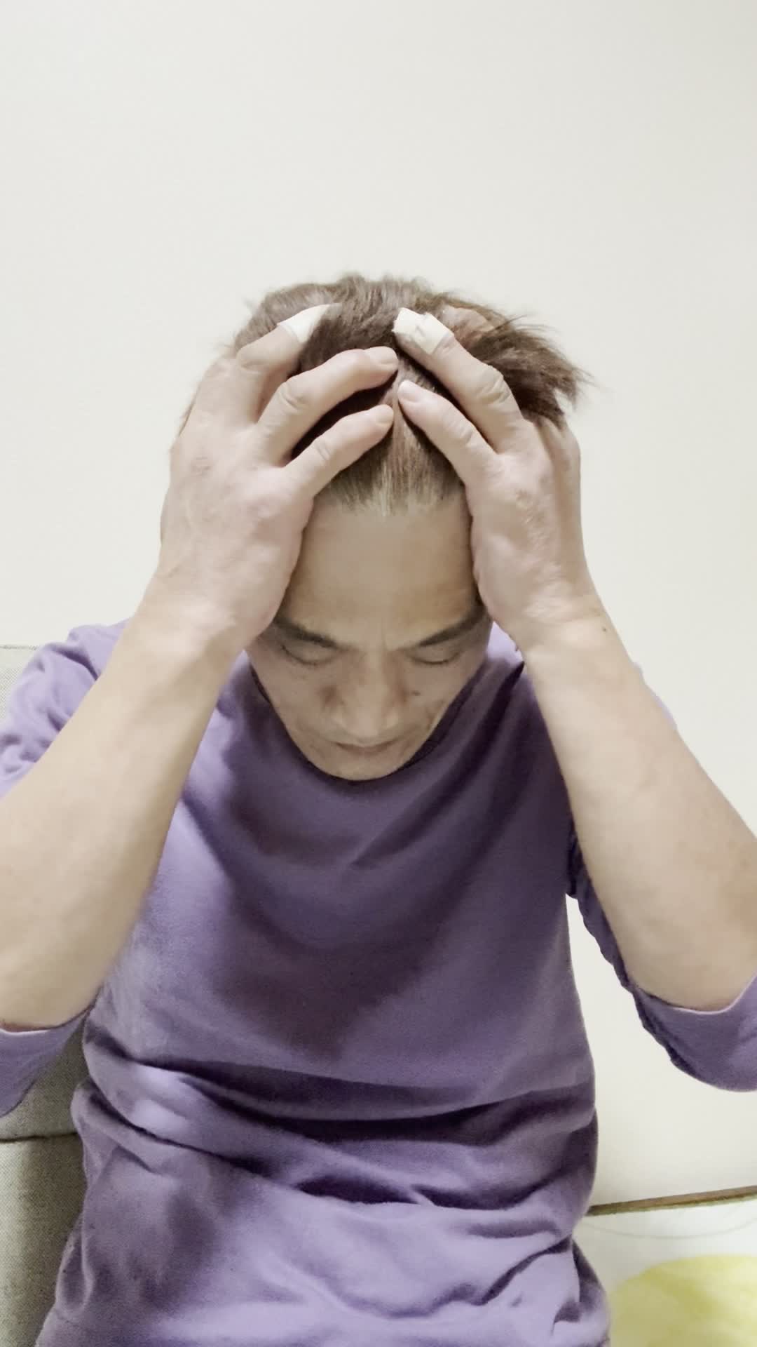 座椅子に腰掛け、両手で顔を覆い、悩んでいる様子を表現する