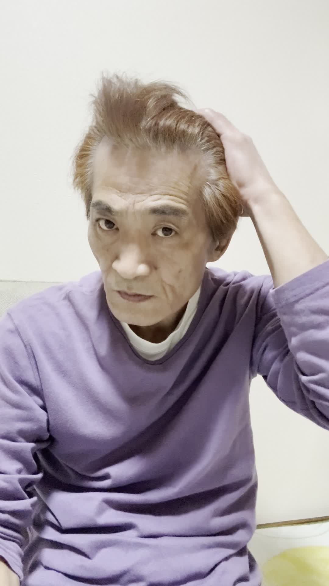 椅子に座りながら、手で髪を軽く整える自然な仕草をする