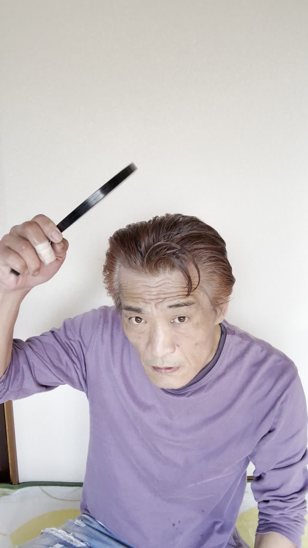 床に膝をつき、鏡を持って頭頂部を確認する仕草をする