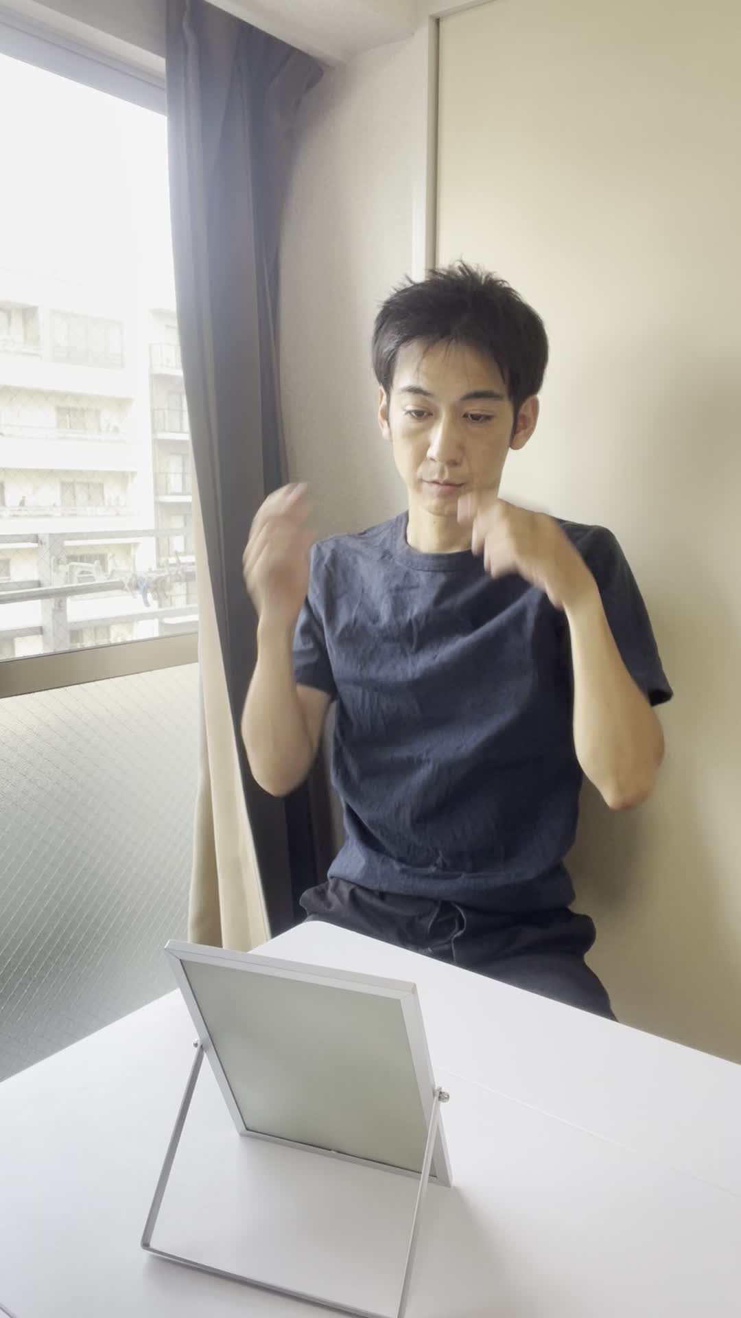 鏡の前で髪の分け目をじっと観察しながら少し真剣な表情を見せる