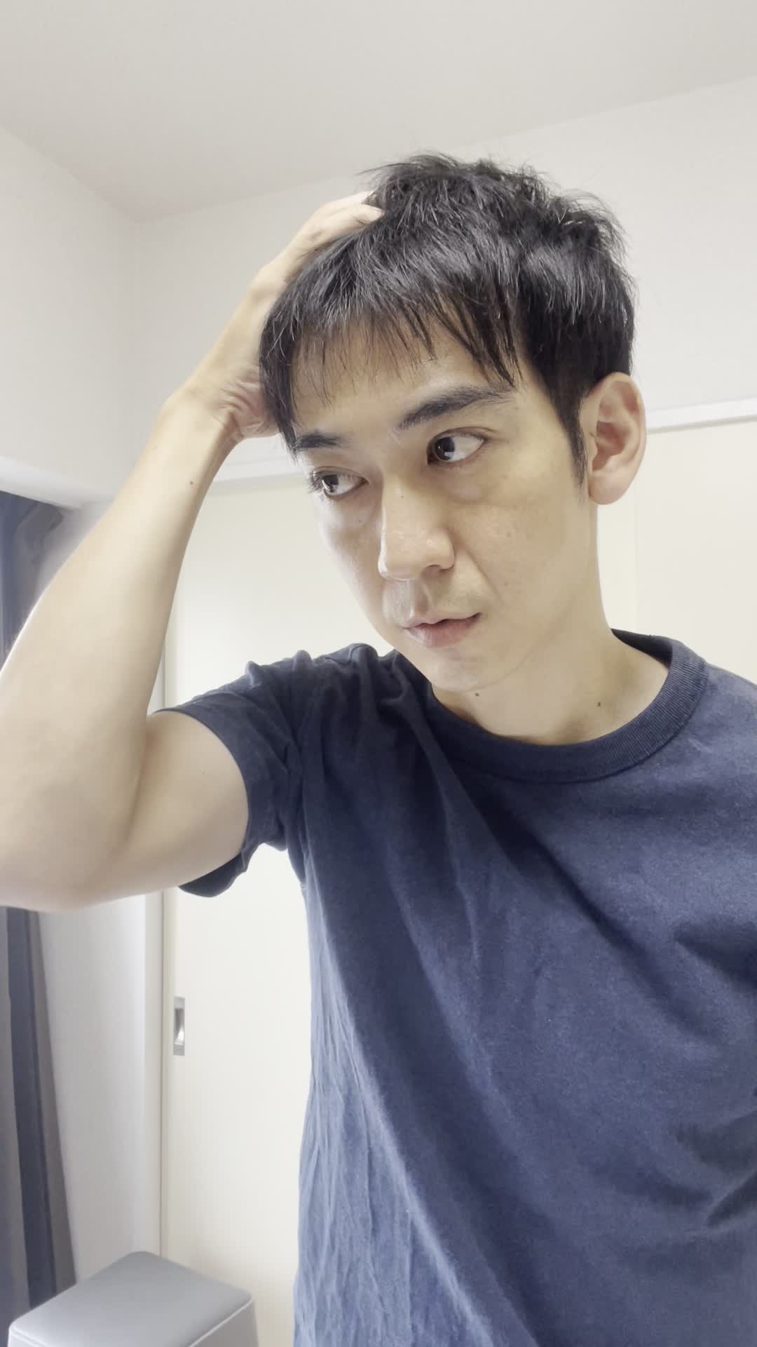 頭皮を指で押さえながら、真剣に自分を見つめている表情をする