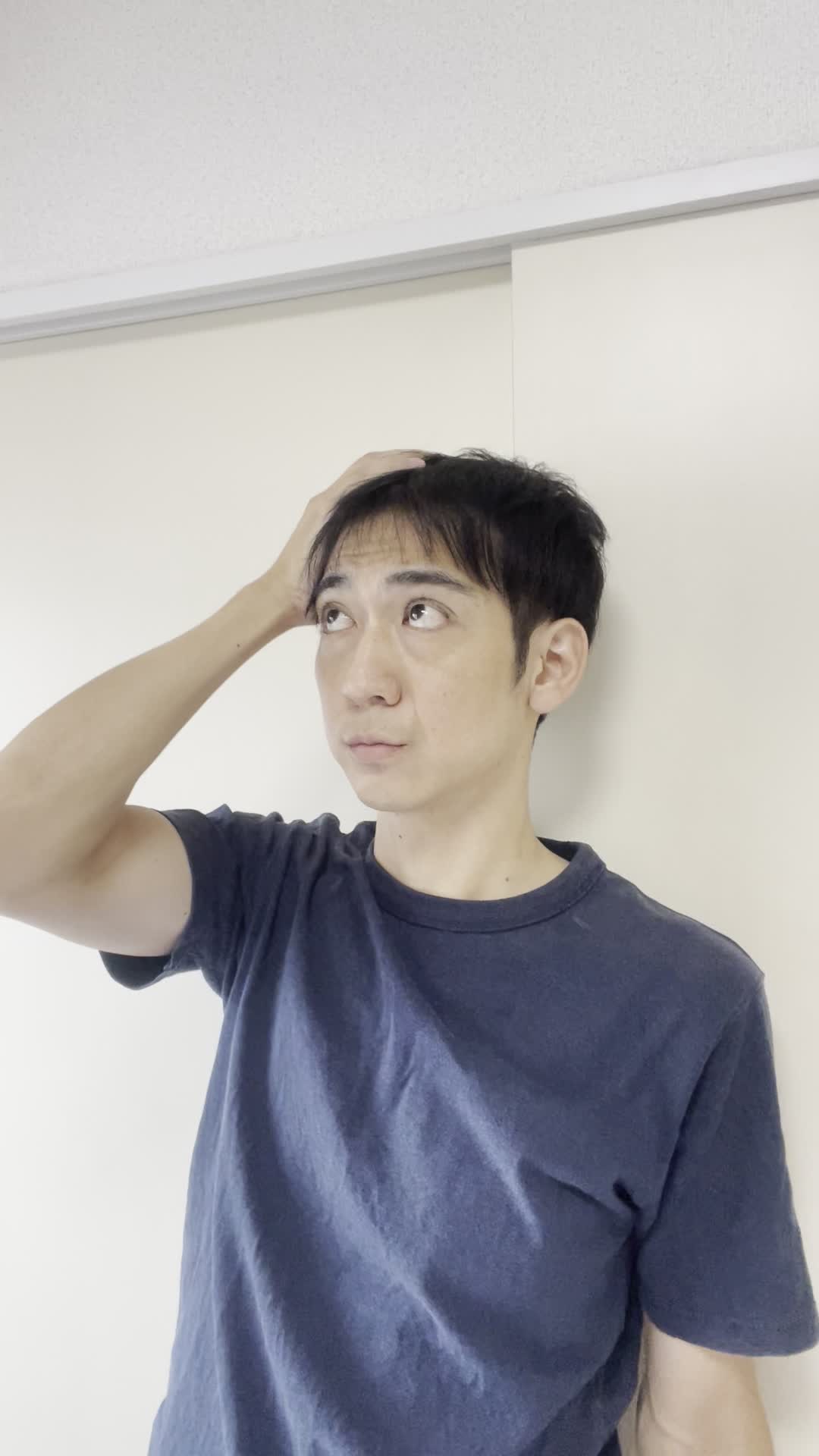 壁に寄りかかり、頭に手を当てて考え込む仕草をする