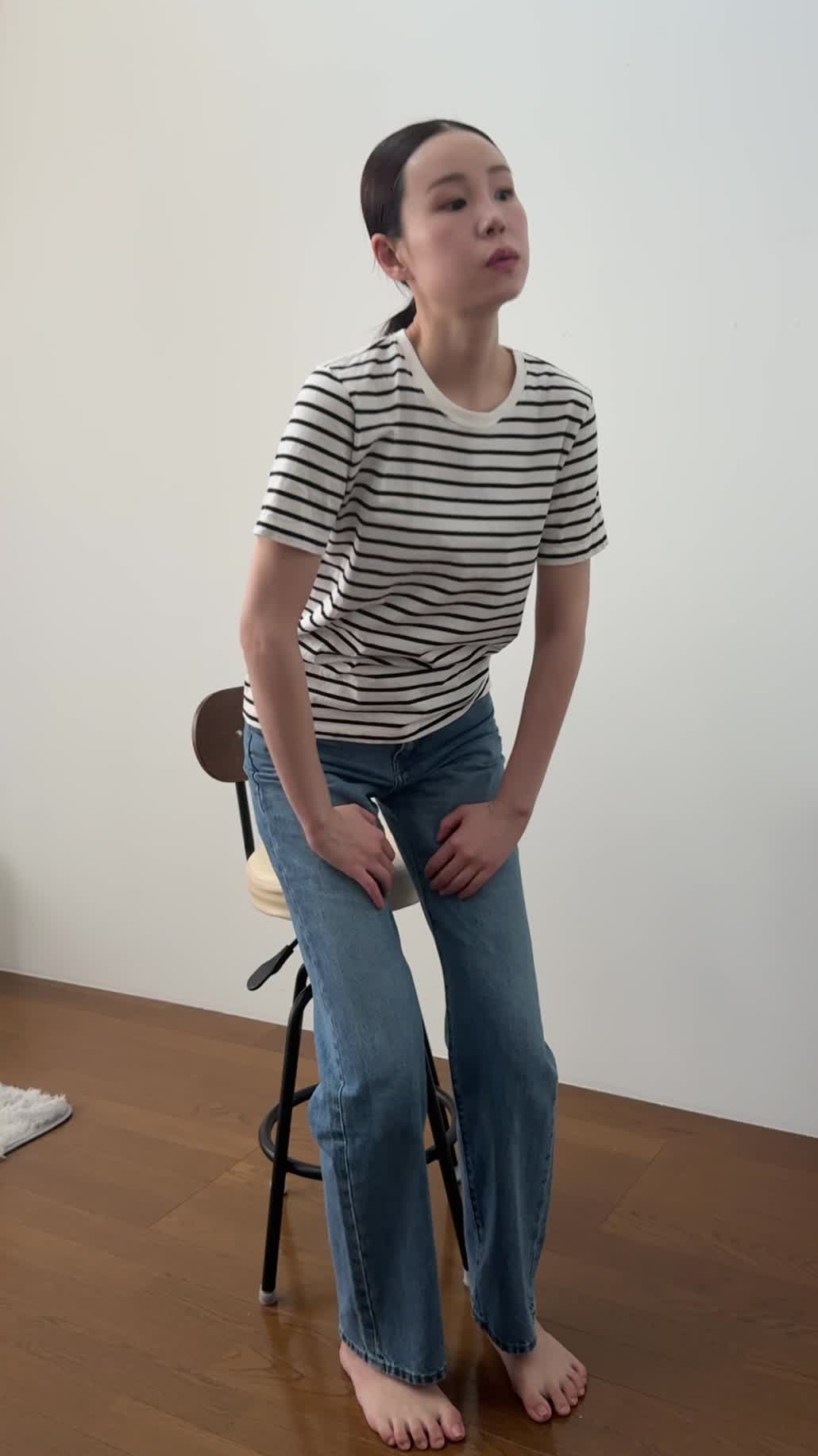 椅子から立ち上がり、「仕事中に疲れが出やすいのがつらい」と肩を回す動作