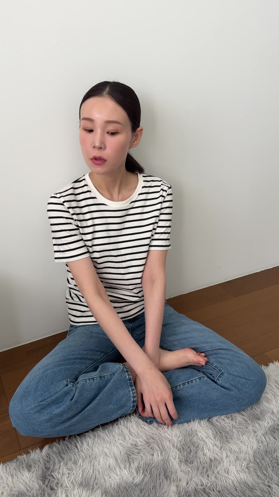 床に膝を崩して座り、「体が重いのは食生活が原因かもしれない」と考え込む姿