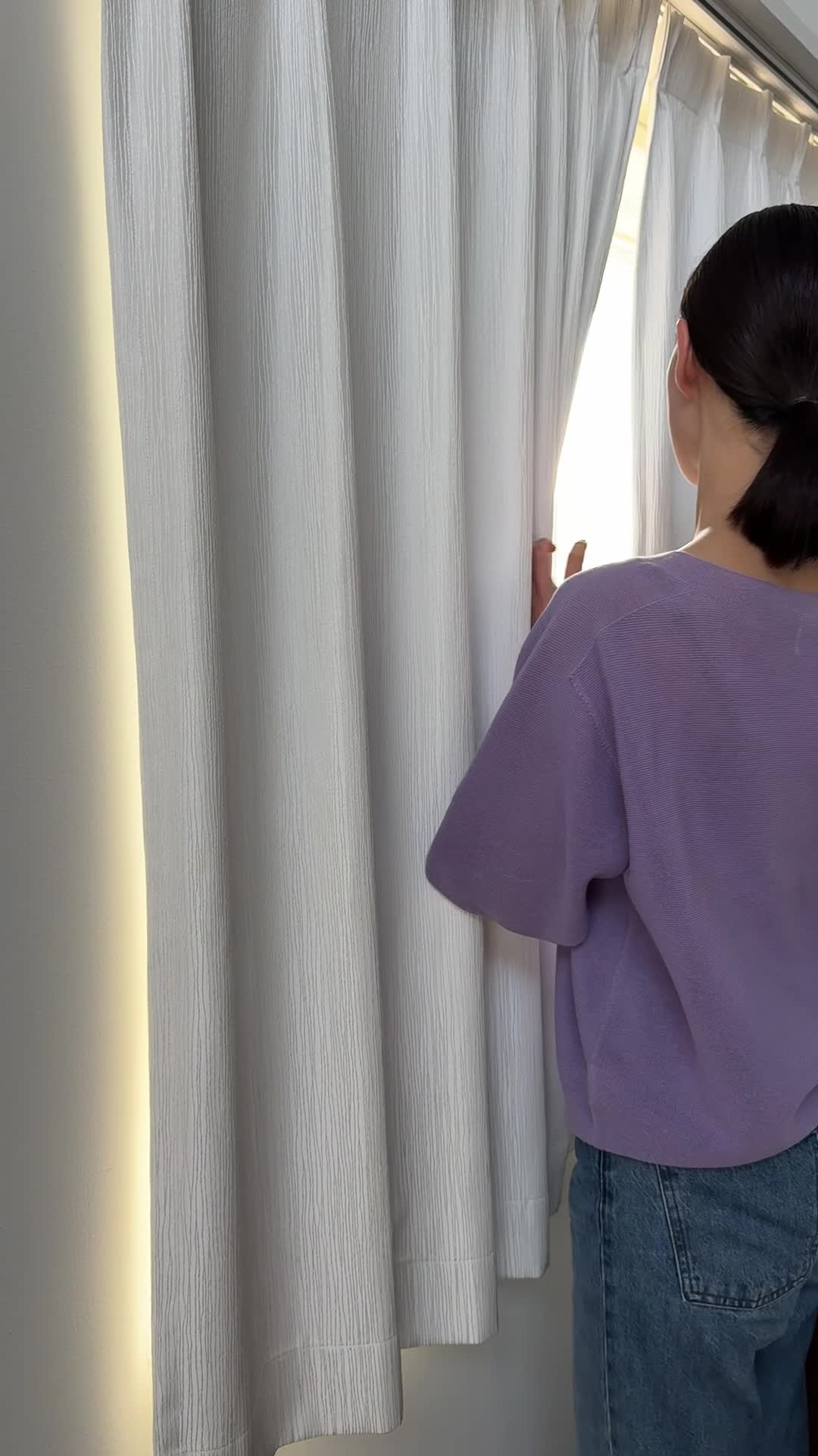 窓の方に歩いて行き、外を眺めながら軽く首を傾げる