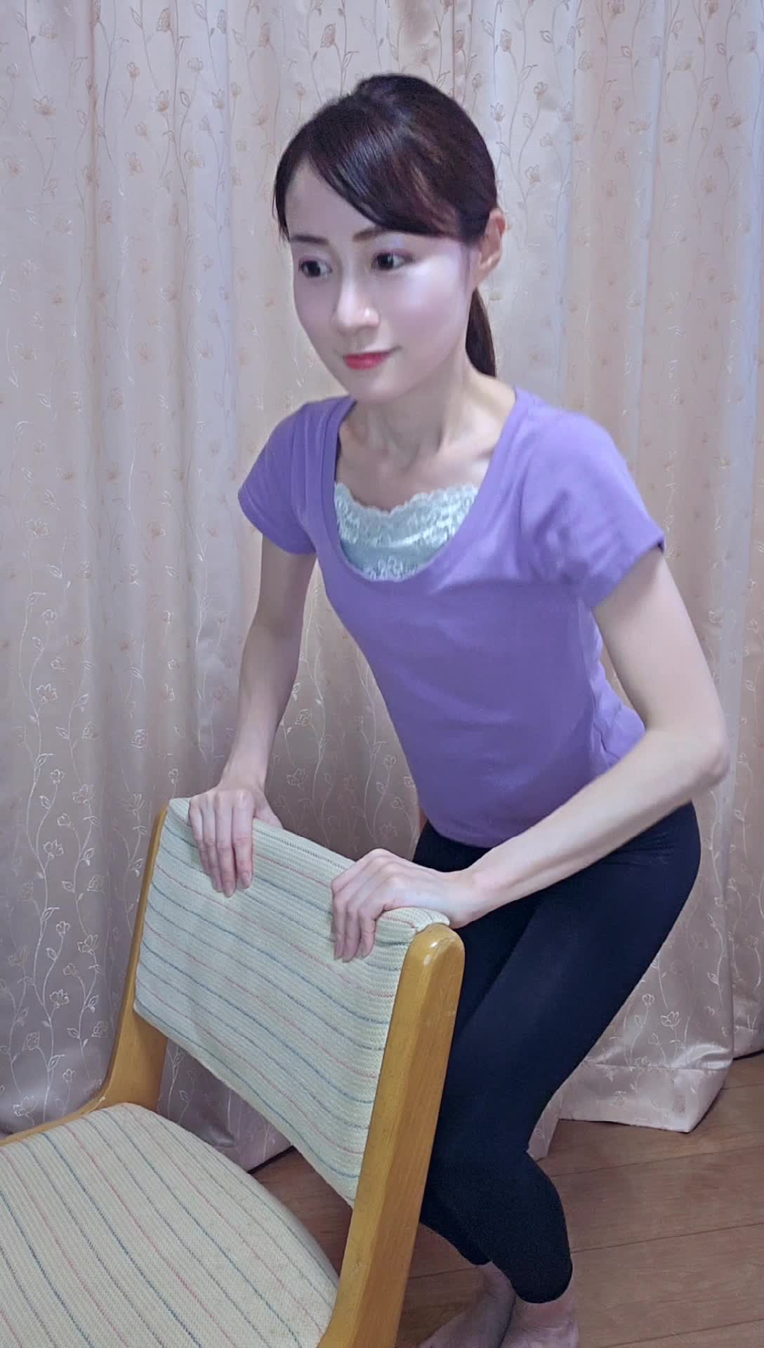 椅子を使ってスクワットをするが、途中でバランスを崩すコミカルな動作