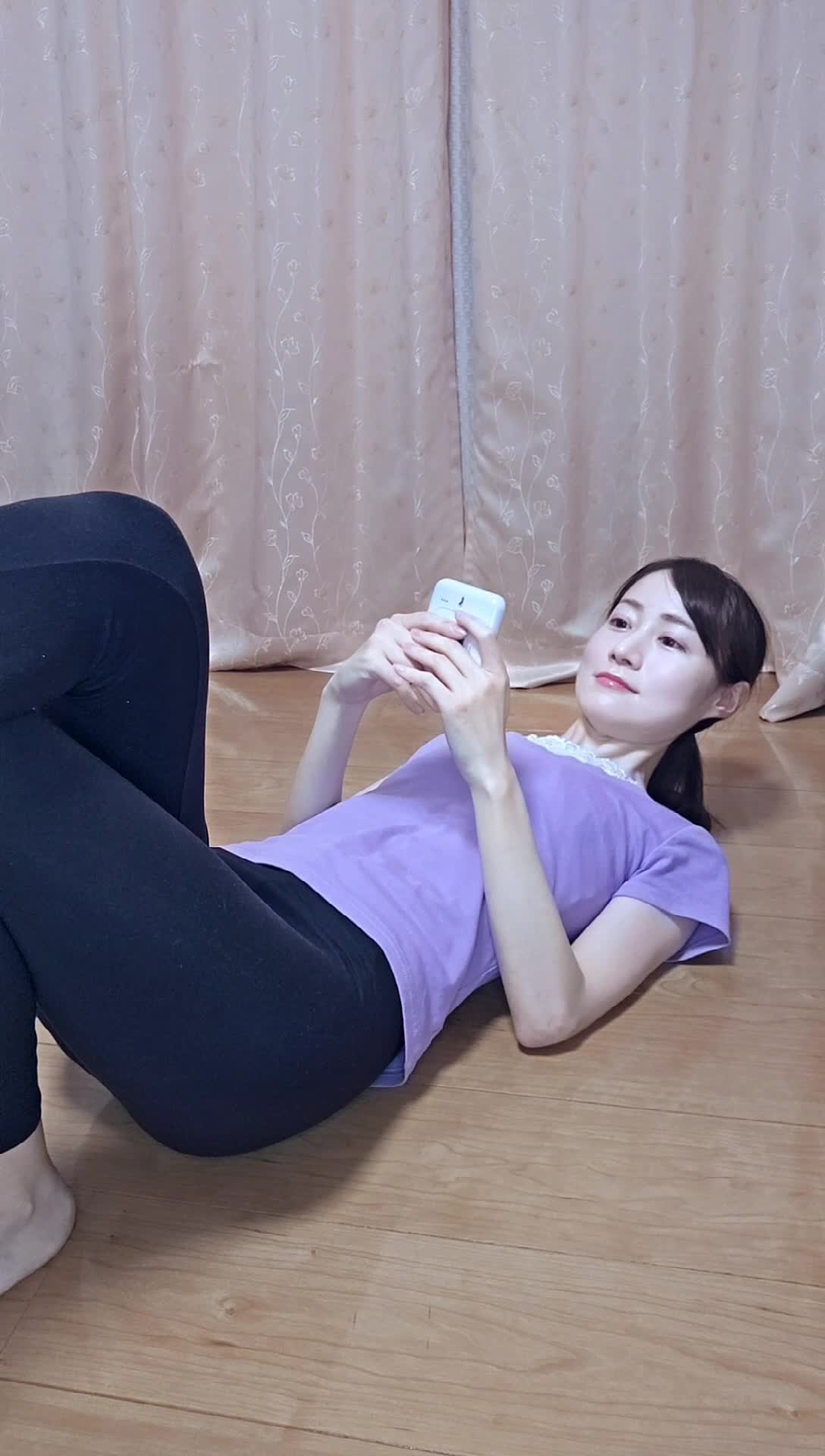 床に寝転び、仰向けになって「1分間プランク」のタイマーをセットする動作