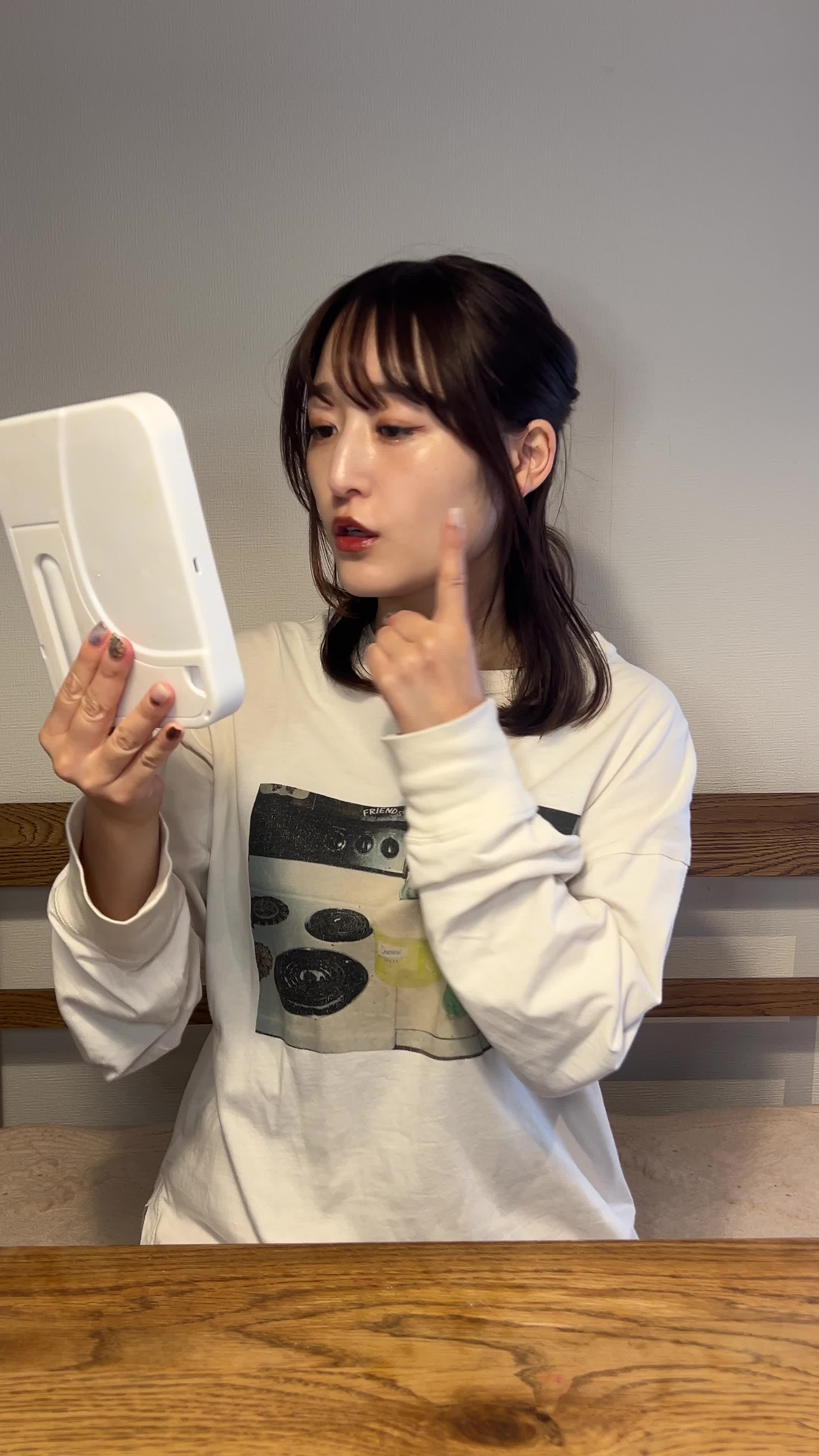 鏡の前で顔を軽く触りながら肌の状態を確認している