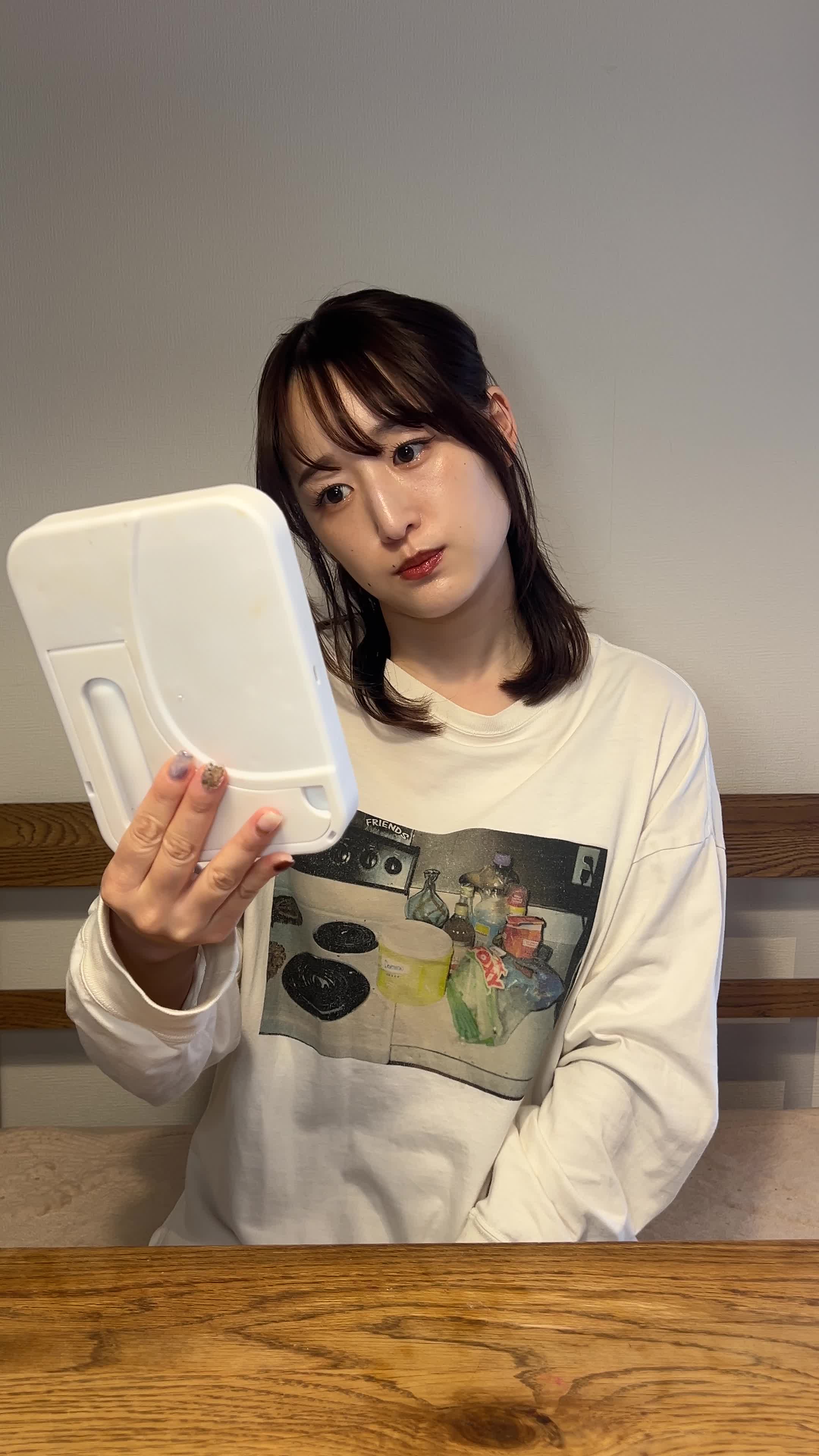 鏡をじっと見つめ、手で顔をかき上げる動作をする