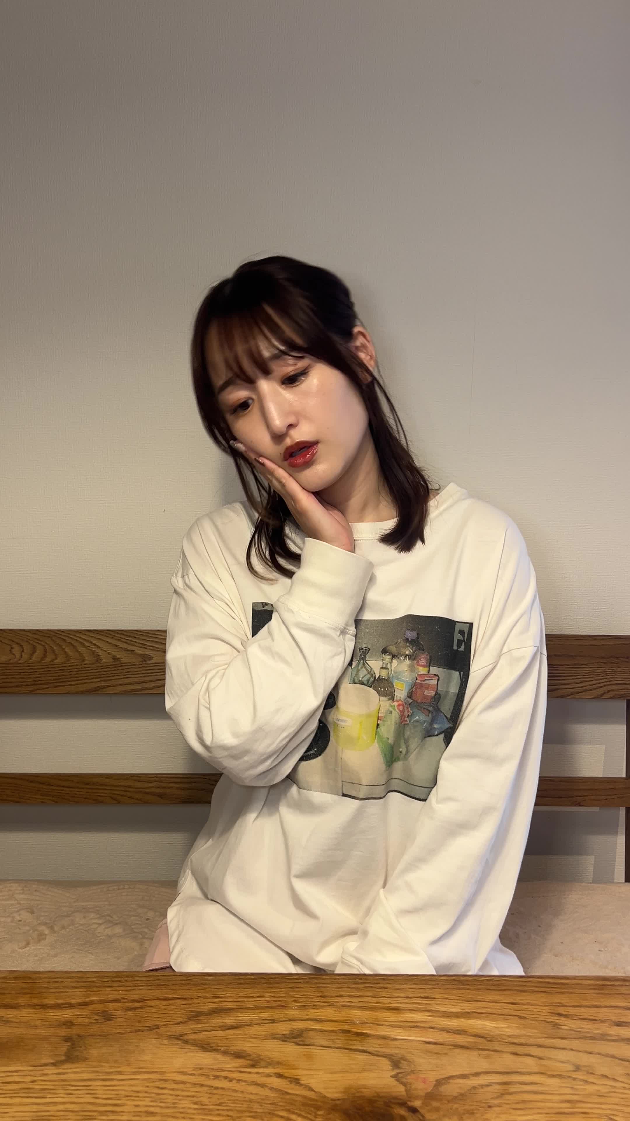 椅子に座り、片手で頬を押さえながらじっと考えている表情を見せる