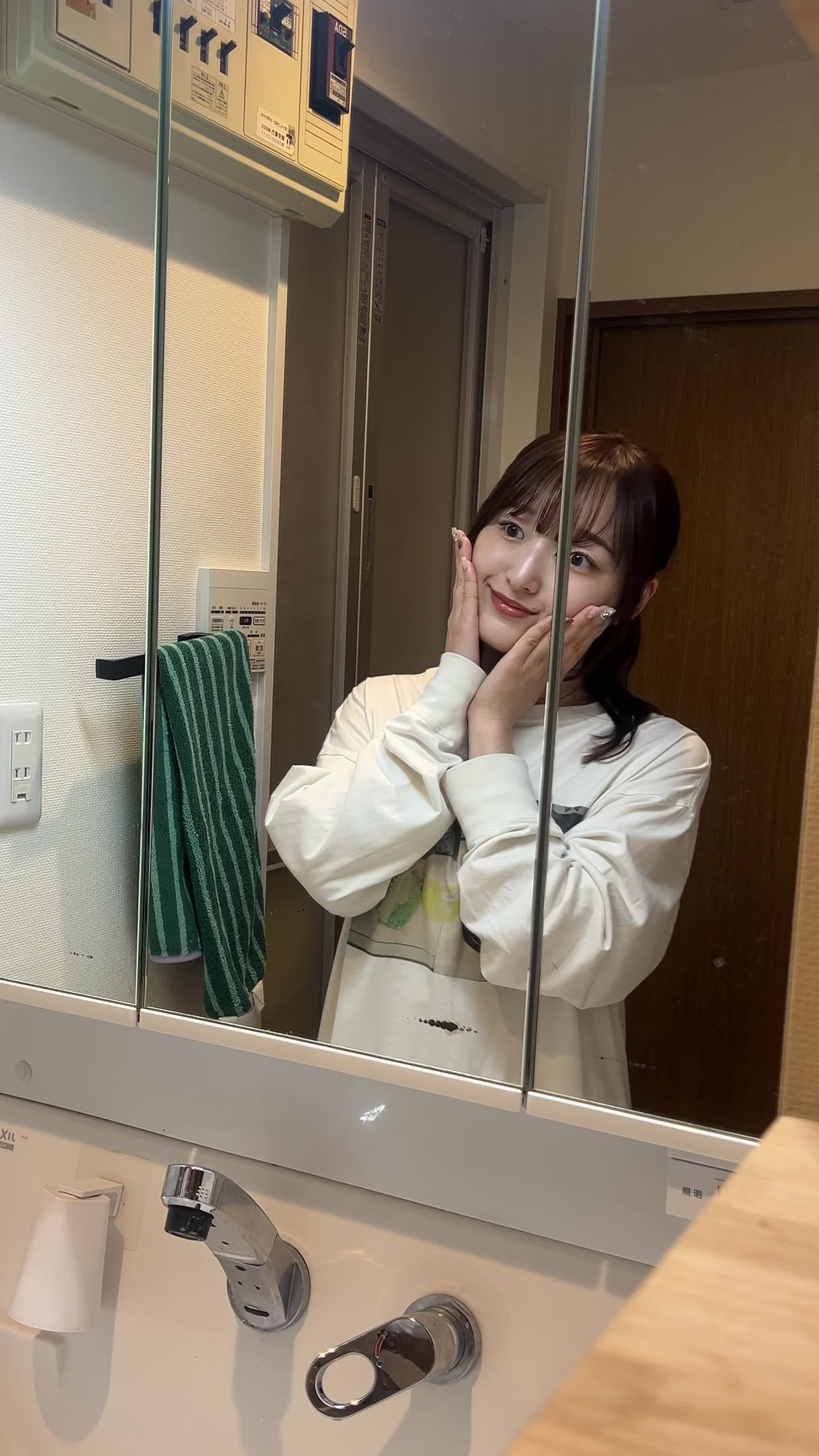 洗面台の前で手を顔に当て、軽くリフレッシュしている仕草を見せる