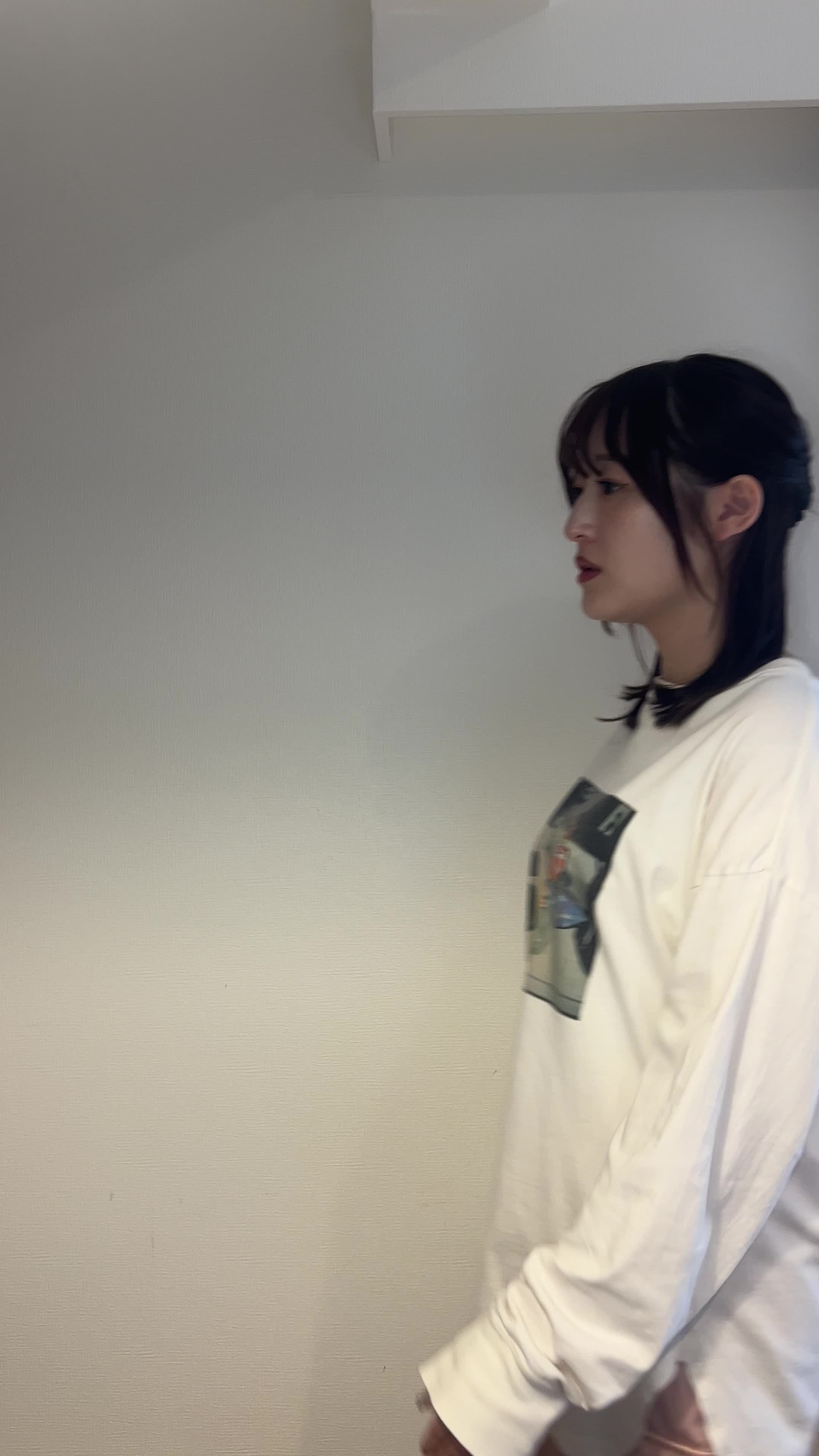 リビングで歩きながらふと立ち止まり、手で頬を触る仕草をする