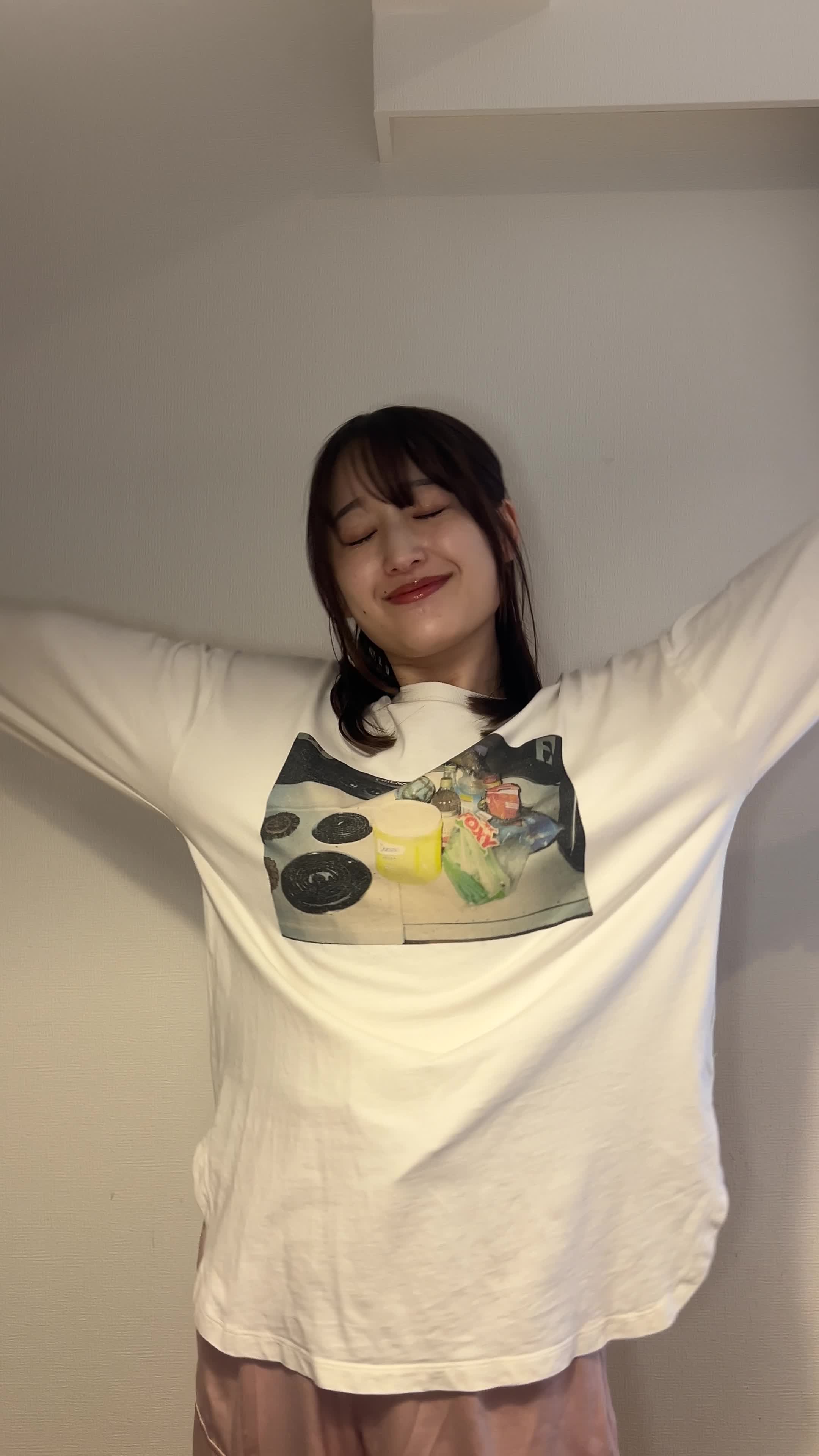 リビングで軽く背伸びをしながら、両手を頬に当てるリラックスした姿