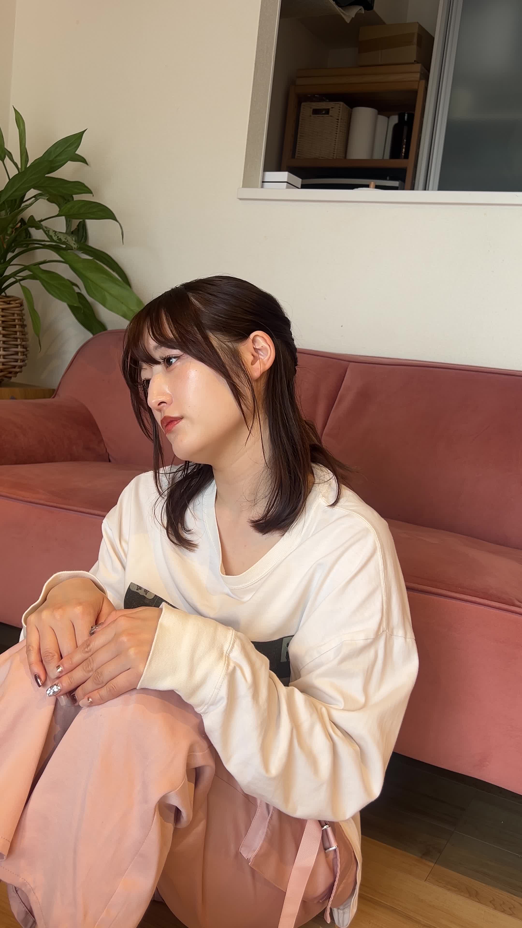 床に座り込み、両手を膝につきながら顔を横に向けて肌を確認している