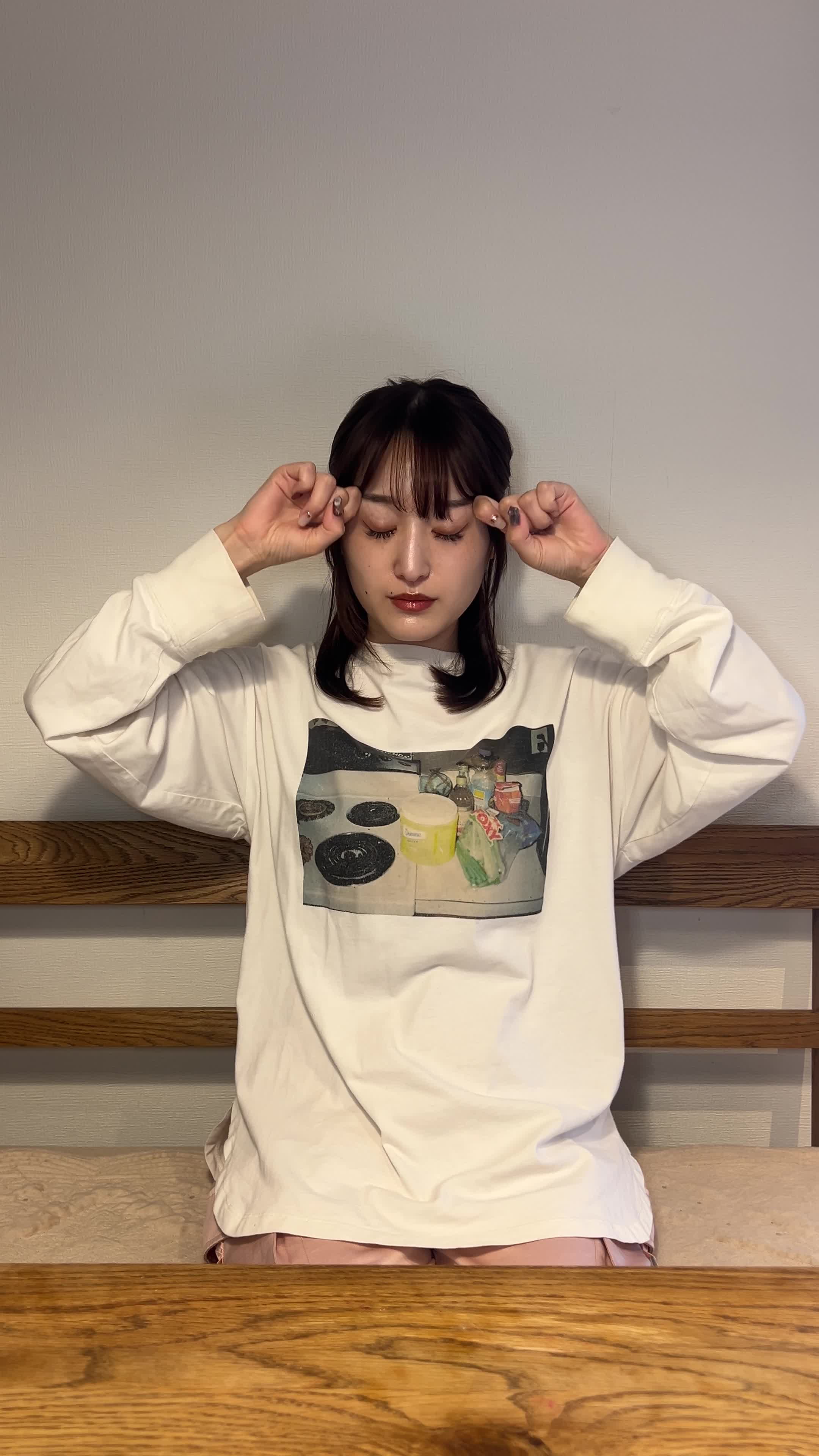 椅子に深く座り、両手で目の周りを軽くマッサージしている様子