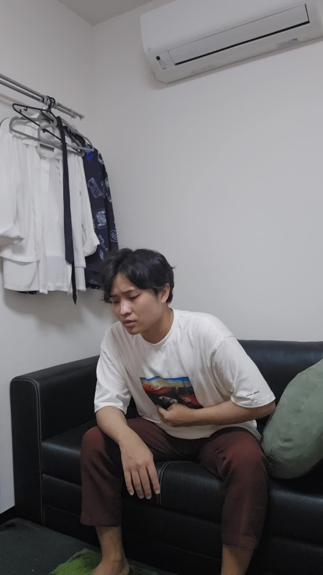 ソファで膝を抱え、「体がだるくて動けない」と頭を抱える様子