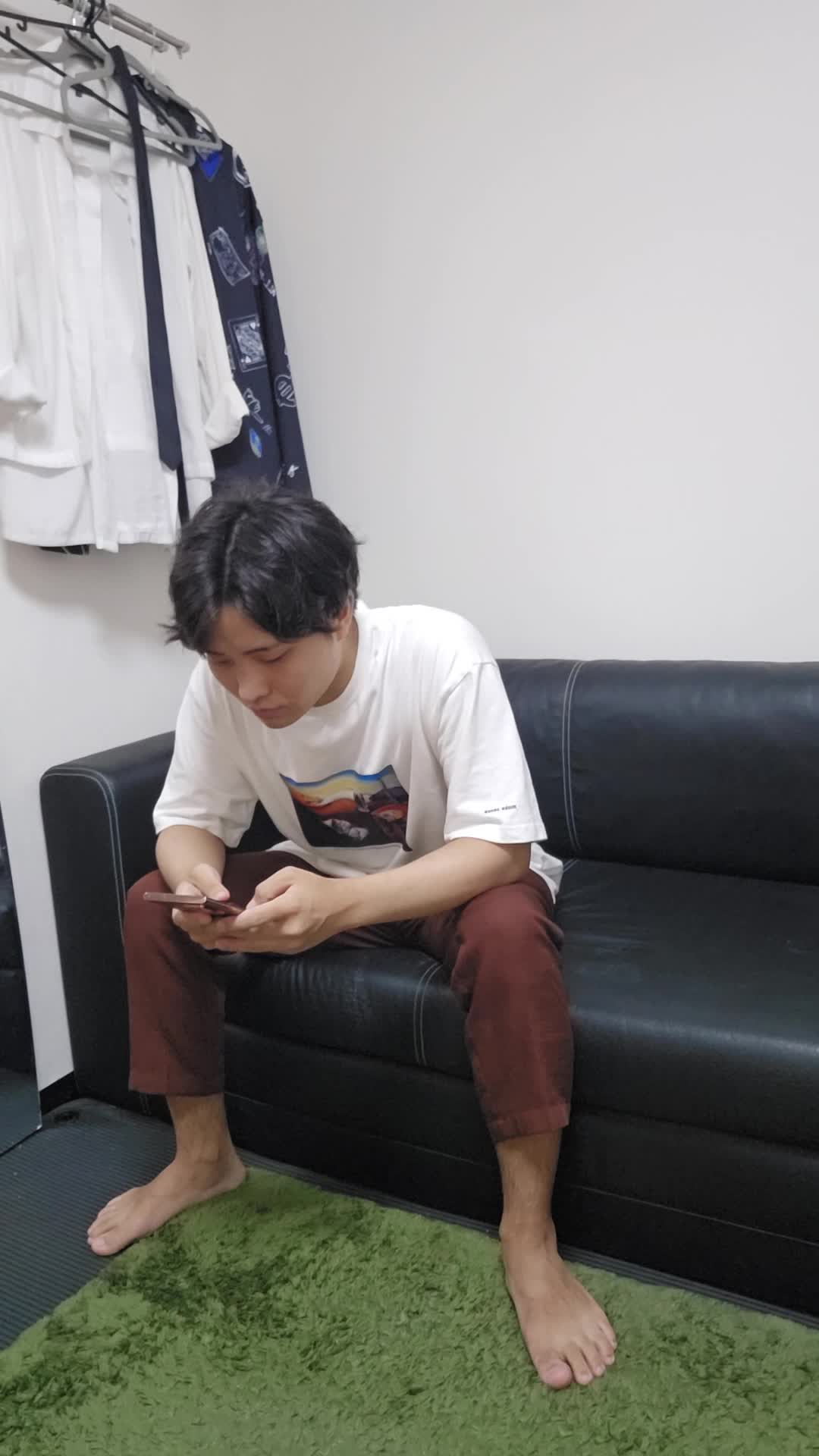 ソファでスマホを見ながら、「腸活の方法を見つけて試したいけど迷う」表情