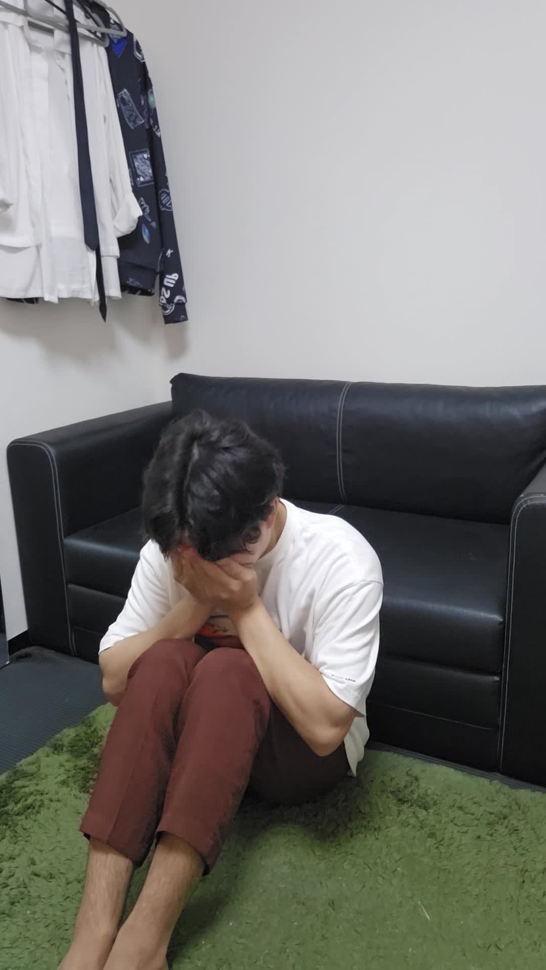 床で顔を両手で覆い、「腸の不調が続くせいで疲れが取れない」と落ち込む表情