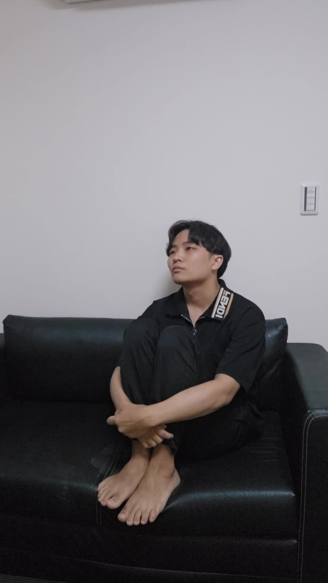 ソファで膝を抱え、「疲れやすくて何もする気が起きない」とため息をつく様子