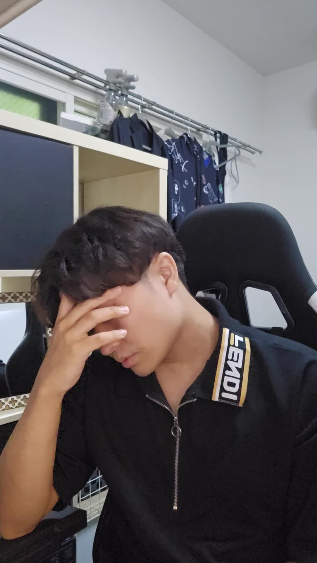 椅子に座り、手でこめかみを押さえながら「最近ずっと頭が重い」と困った表情