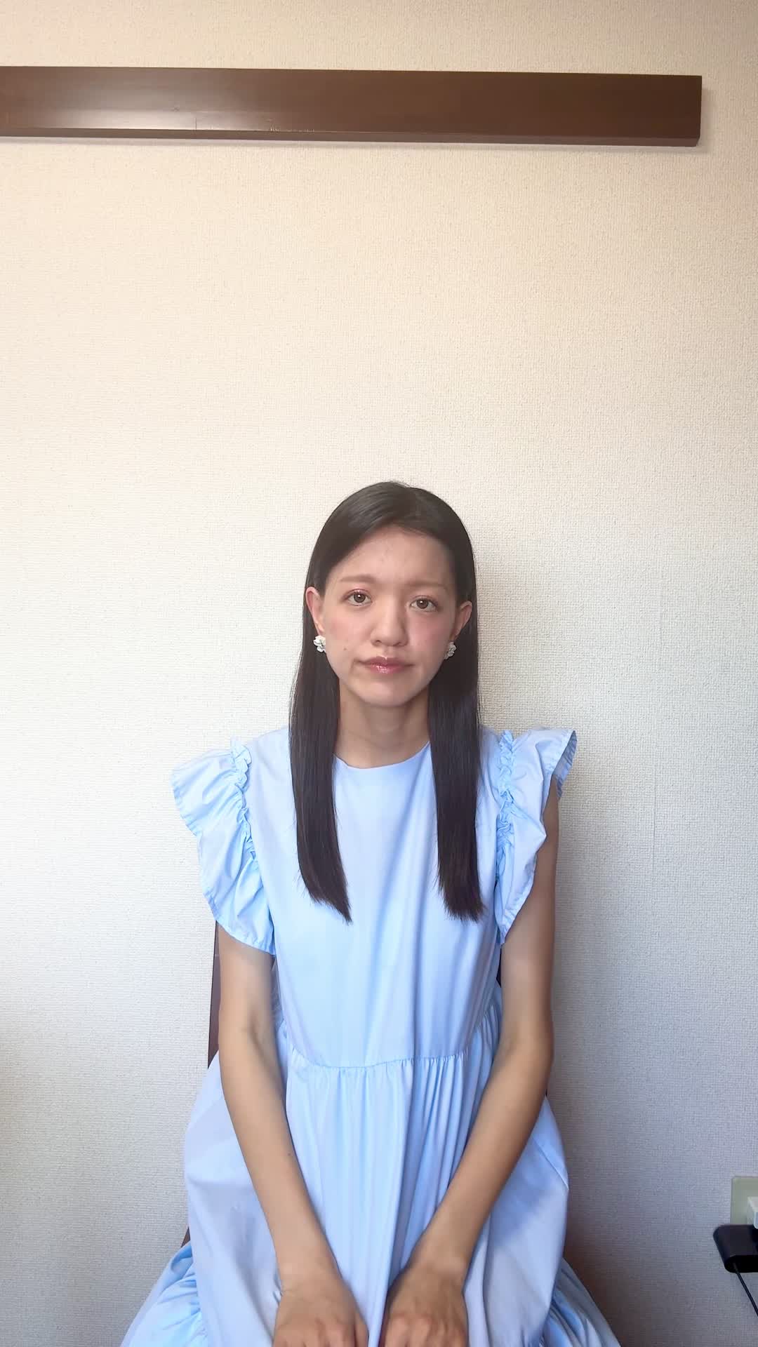 椅子から立ち上がり、「仕事中に疲れが出やすいのがつらい」と肩を回す動作