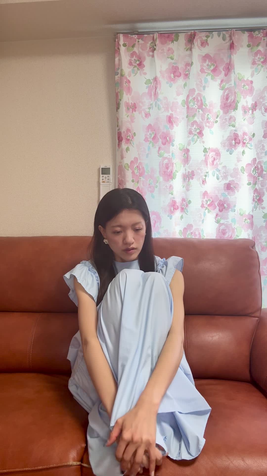 ソファで膝を抱え、「疲れやすくて何もする気が起きない」とため息をつく様子