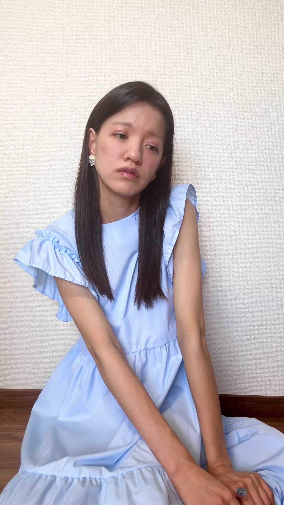 床に膝を崩して座り、「体が重いのは食生活が原因かもしれない」と考え込む姿