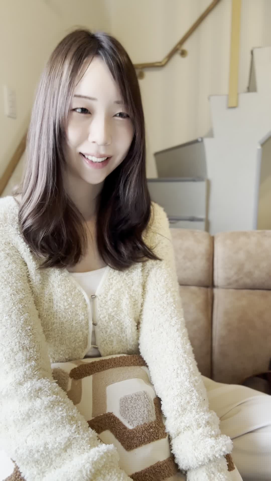 ソファで友達と話しながら、「自分の歯並びが気になる」と口元を隠す仕草