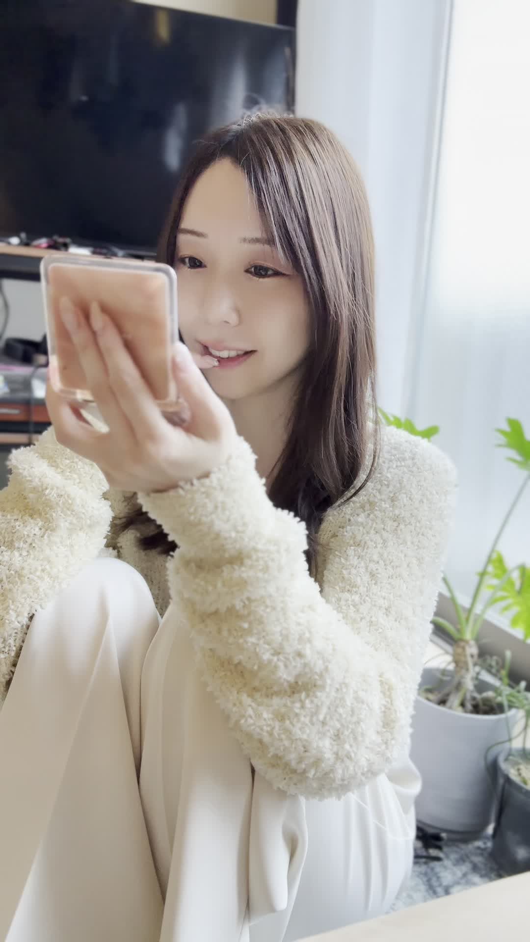 床に座り込み、手鏡で自分の歯をじっくり観察し、「これが変わるかな？」と期待する表情