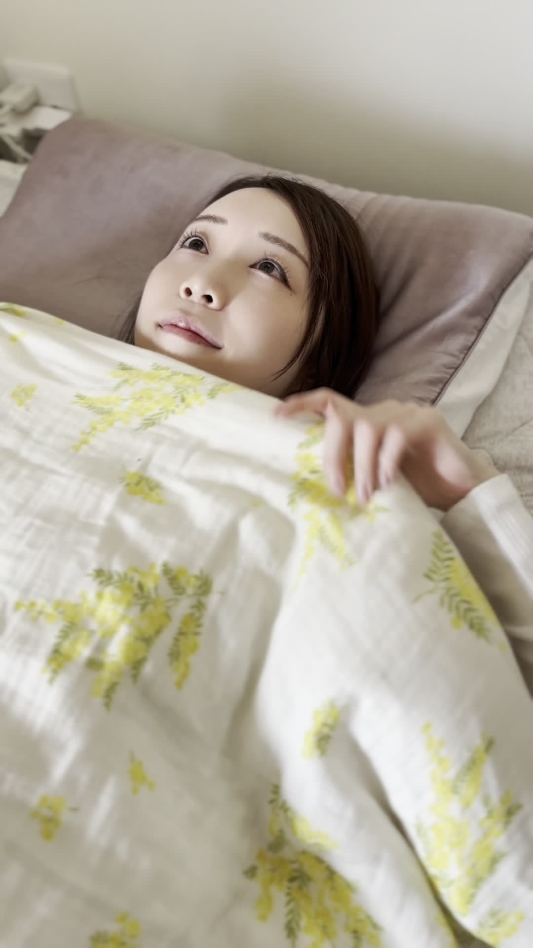 ベッドで横になり、「笑顔がもっと綺麗になるのかな？」と微笑む様子