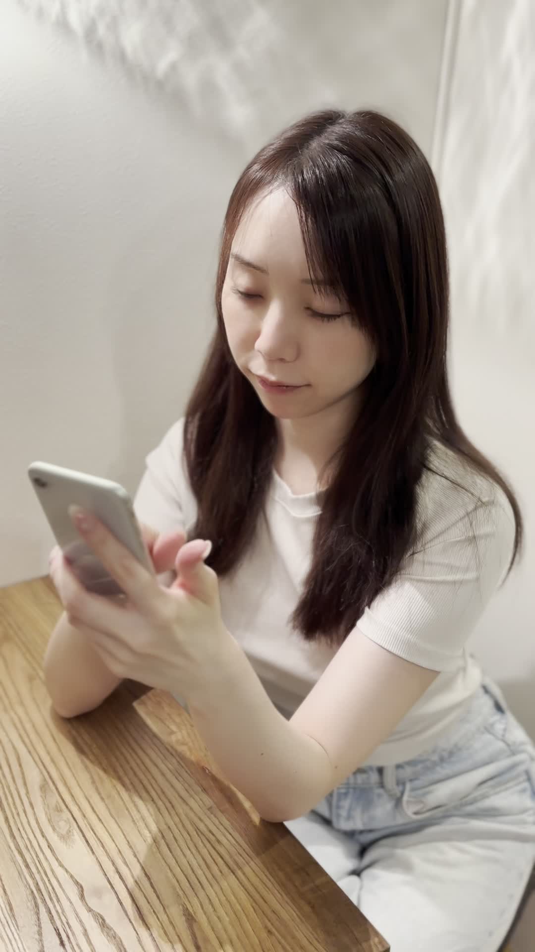 椅子に座り、スマホでカートの中身を確認しながら「これ全部買おうかな？」と悩む表情