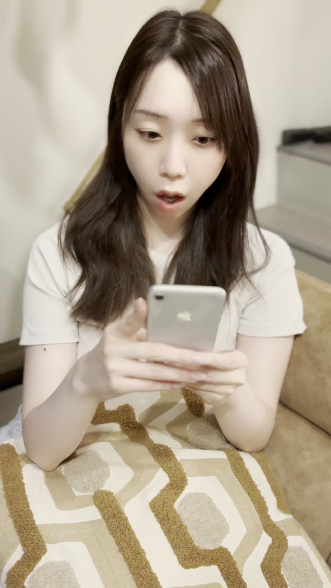 ソファでクッションを抱え、スマホの画面を見て「これがタイムセール価格？」と驚く様子