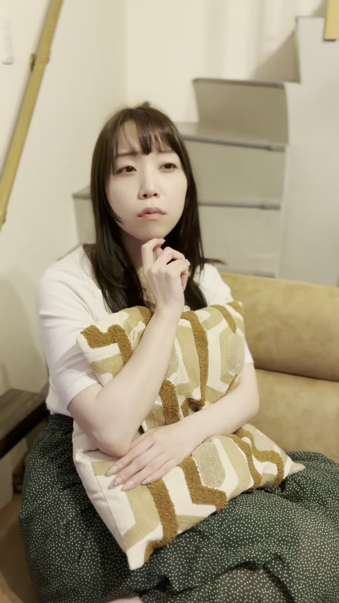 ソファでクッションを抱え、「これで匂いが改善するかな？」と悩む真剣な表情