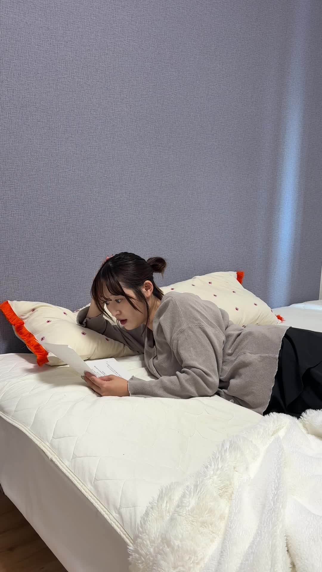 ベッドで横になりながら、「キャンペーン、今日までって本当？」とカタログを覗く仕草