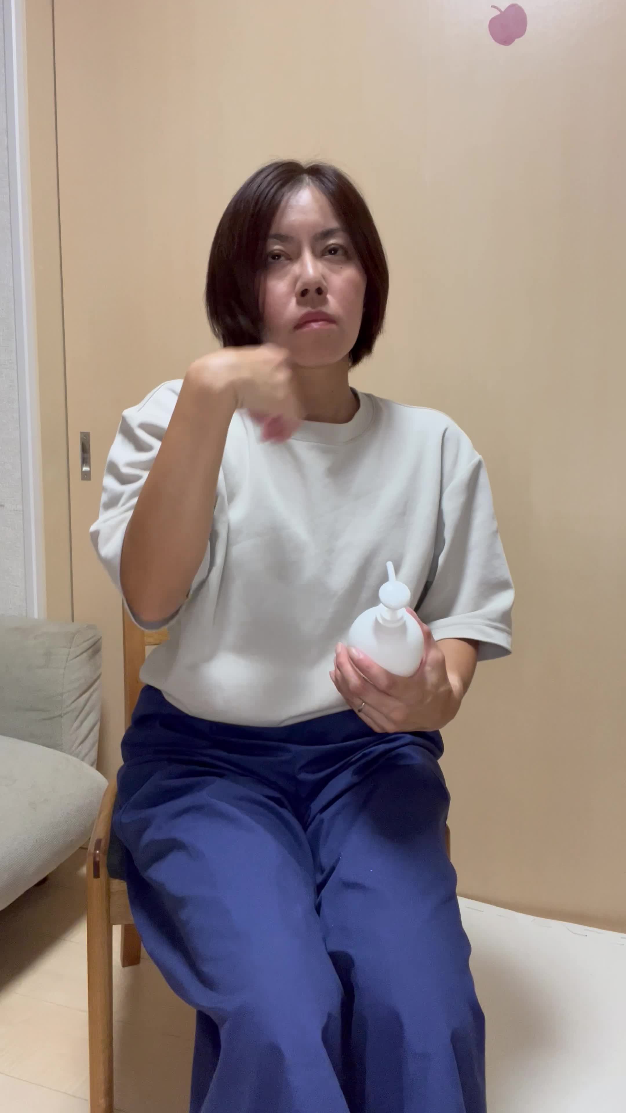 椅子に浅く腰掛け、髪を手ぐしで整えながら「このシャンプー試してみよう」と決意する表情