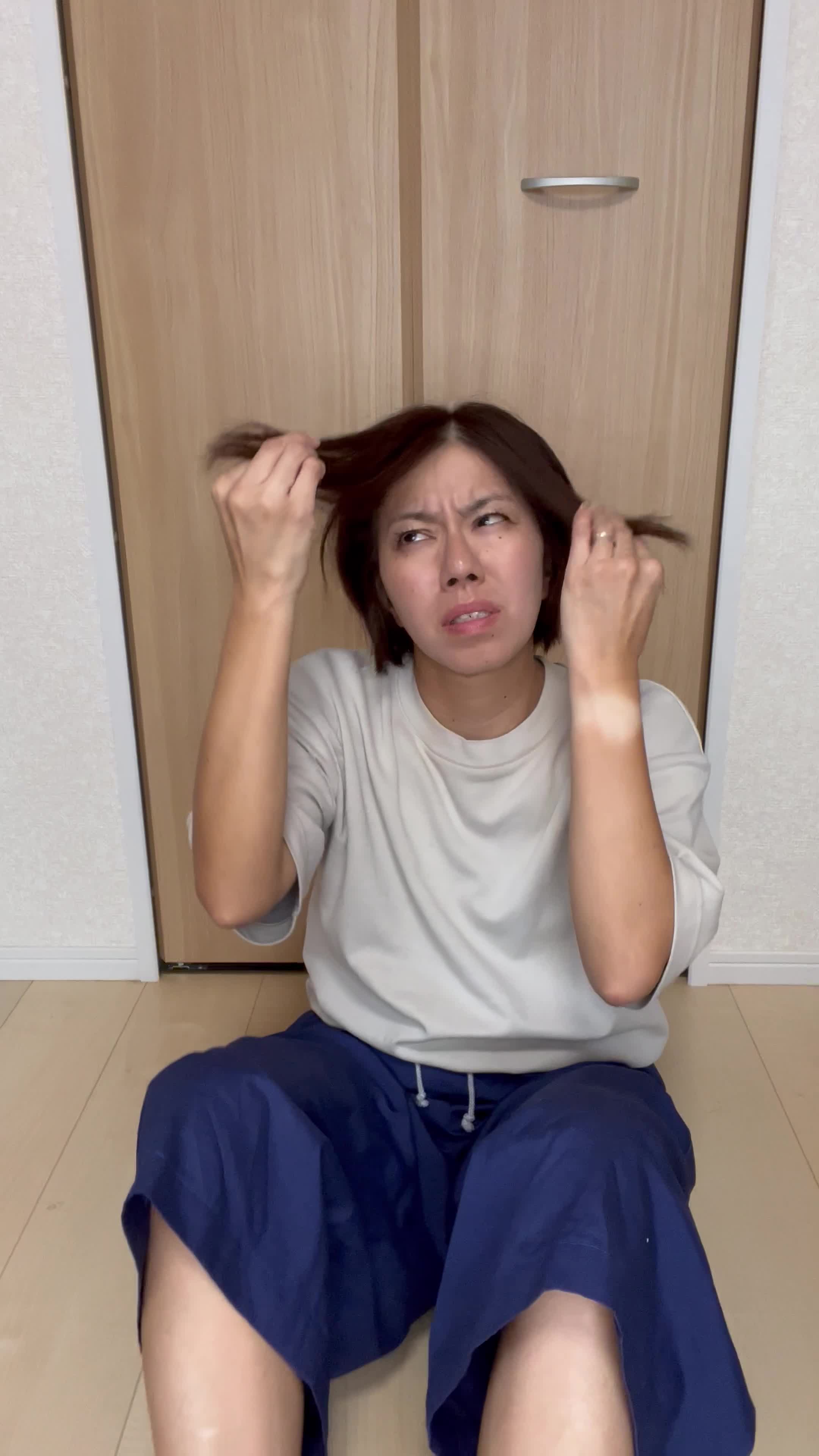 床に座り込み、髪の毛先を見ながら「これじゃデートに行けない」と焦る動作