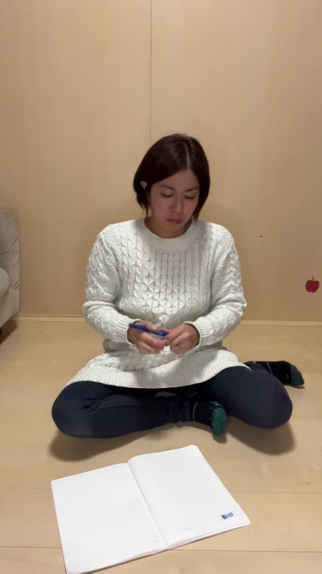 床にノートとペンを広げ、真剣に目標をリストアップする様子を映すシーン