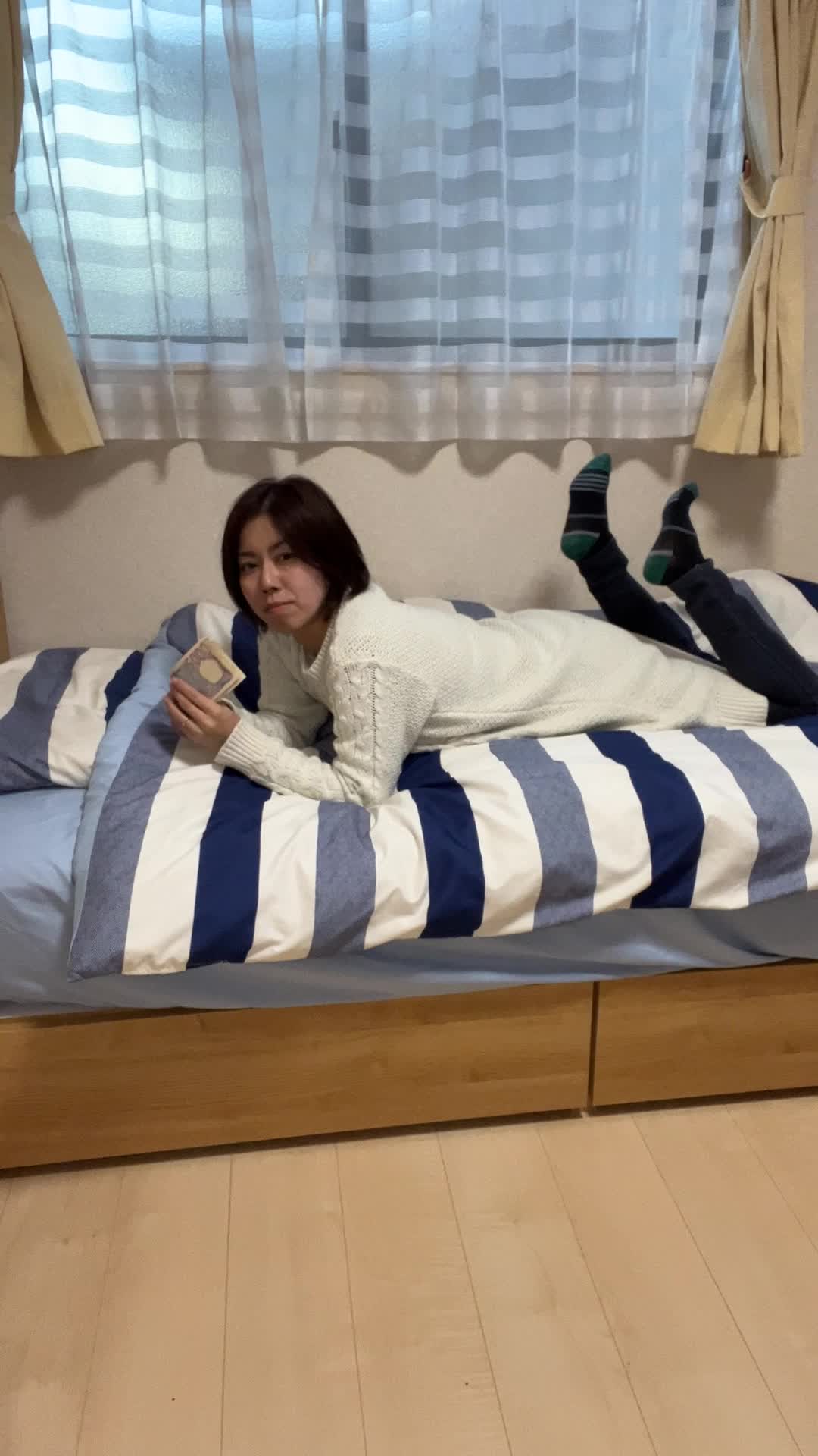 ベッドで寝転びながら、お札を1枚ずつ並べて「将来の資産」を思い描く姿