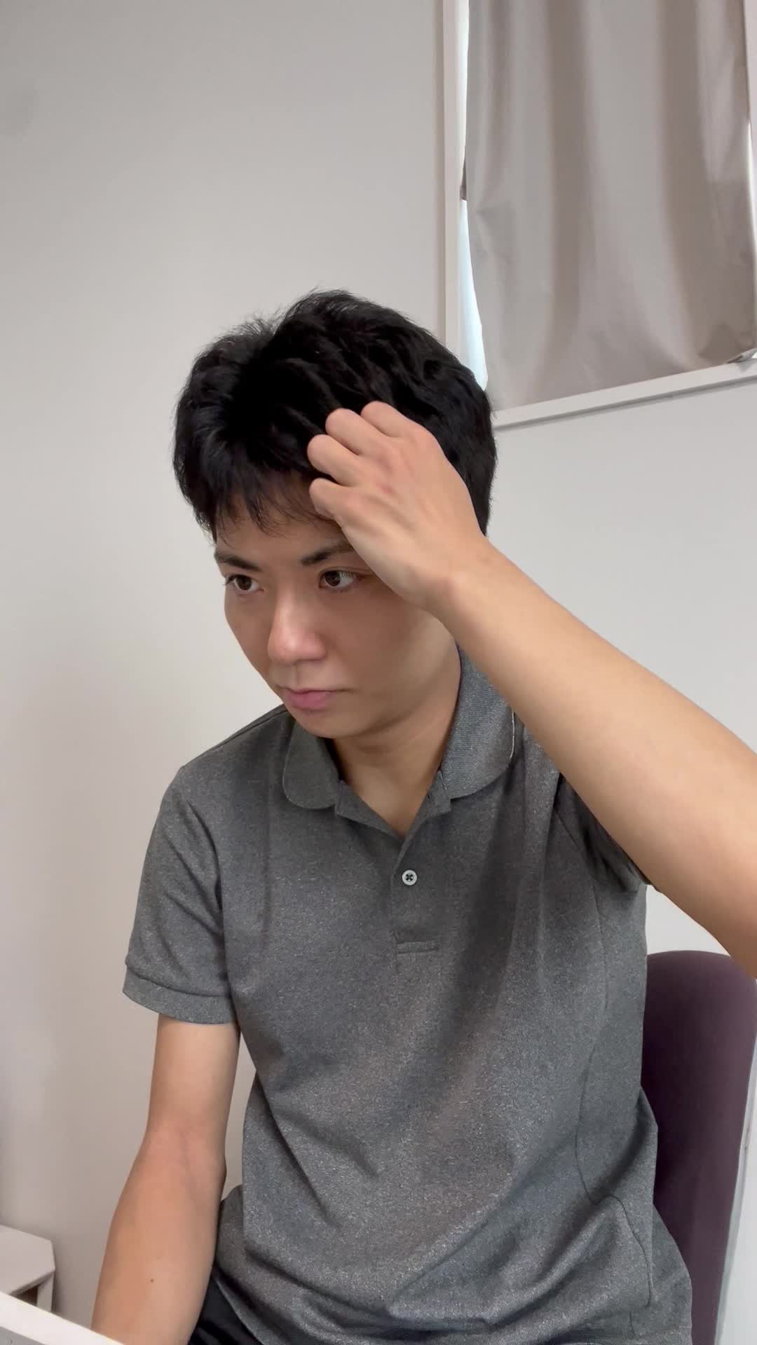 椅子に座り、仕事中に髪のパサつきが気になり、少しイライラする表情を見せる姿