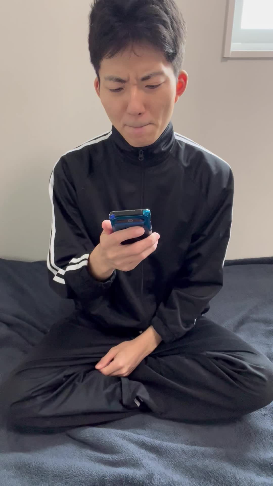 ベッドで連絡が来ないスマホを一瞬投げ出し、「どうしよう」と悩む表情